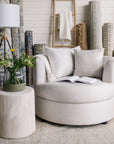 White cuddle chair with a side table and lamp in a room with textured wall coverings in St. Albert.
