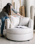 interior designer arranging pillows on a gray cuddle chair in a room with decorative rugs in St. Albert